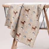 Dog park print muslin swaddle draped over a crib